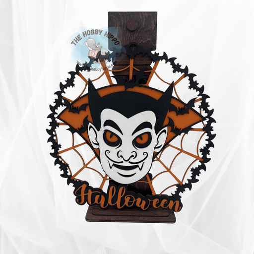 A wooden laser cut wall or door hanger, Halloween decor, DIY paint kit, had a spider web with Dracula’s face and says Happy Halloween